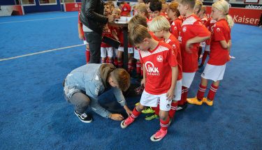 Torben Müsel gibt ein Autogramm auf dem Schuh eines Kindes