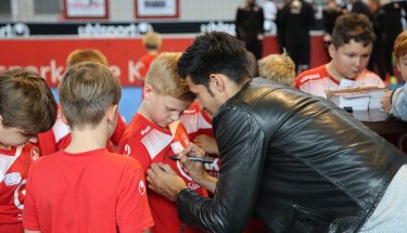 Marcel Correia unterschreibt auf dem T-Shirt eines Kindes